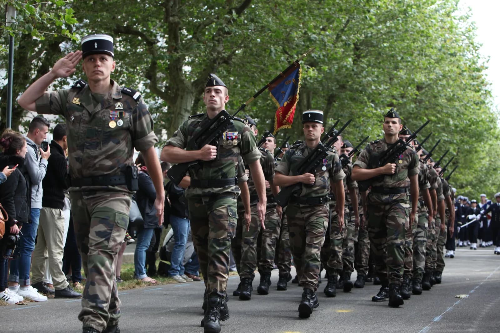 Élèves gendarmes en treillis défilant avec leur drapeau lors d'une cérémonie du 14 Juillet à Brest