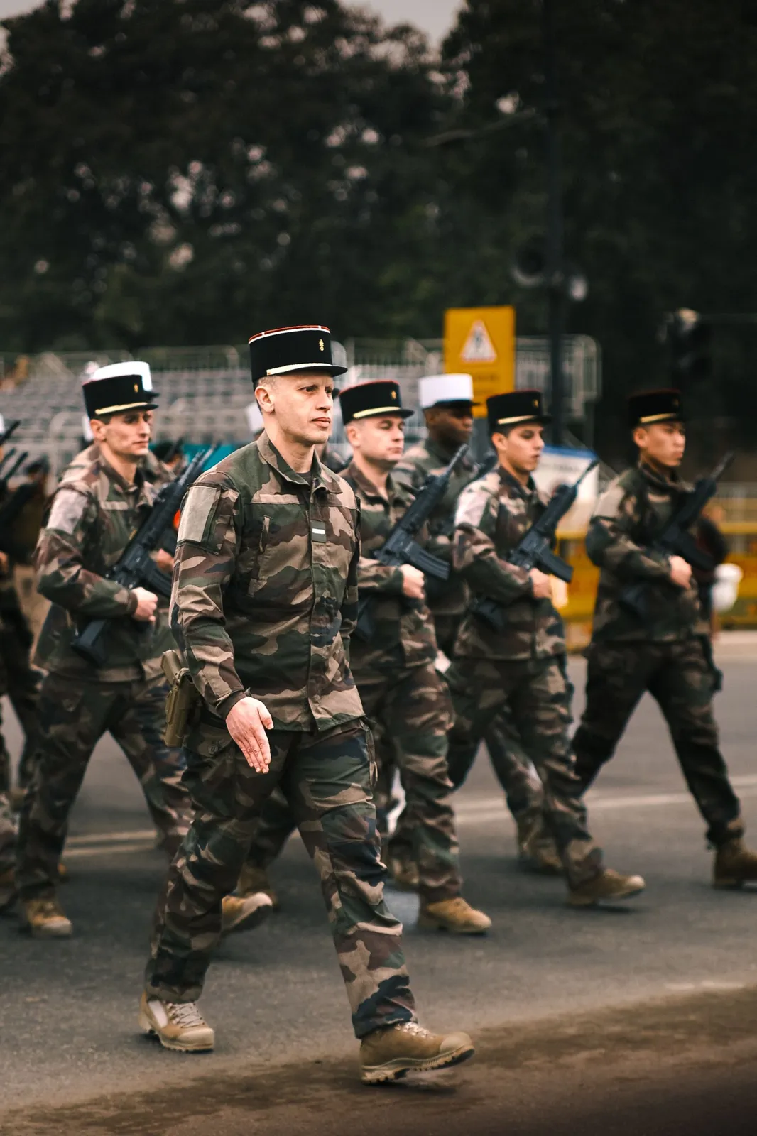 Légionnaires en képi blanc défilant derrière leur cadre en képi noir